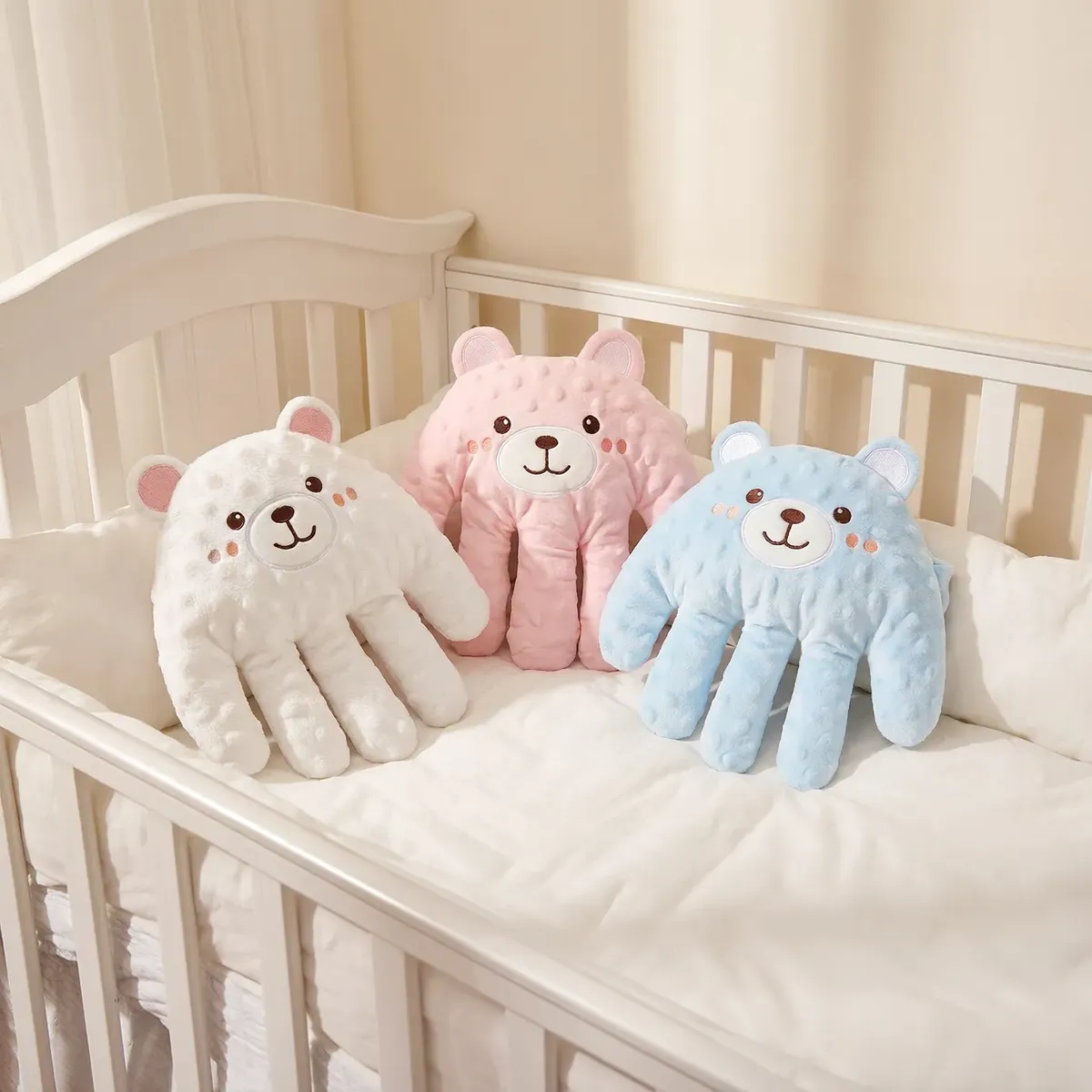 Peluches con forma de mano en tres colores, blanco, celeste y rosa.